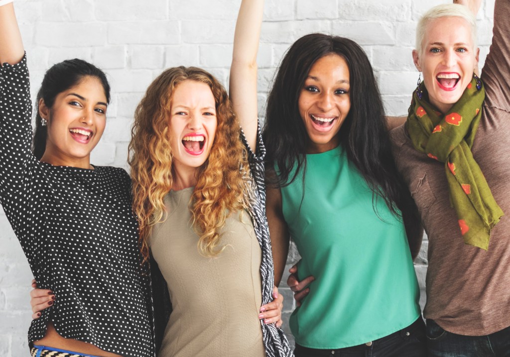 group of women smiling raising their arms in the air